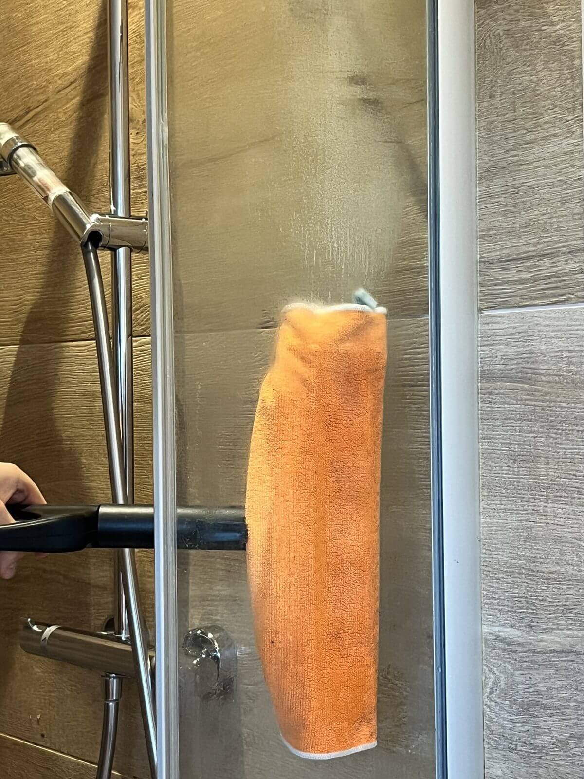 Passage de la brosse et de sa microfibre sur une paroi de douche à la vapeur sèche, à Guérande